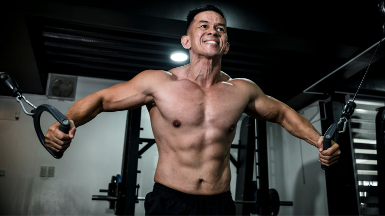 Muscular person in gym performing cable chest exercise