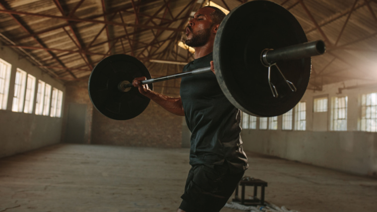 Person in gym straining to lift barbell