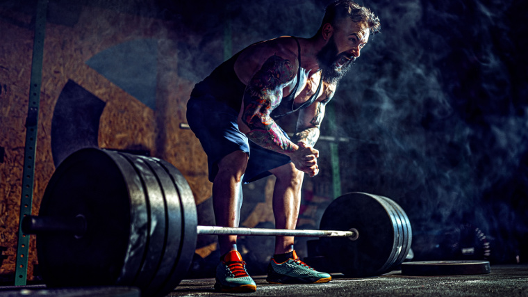 Muscular person in gym preparing to lift heavy barbell