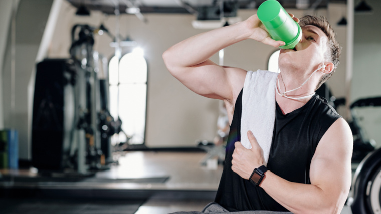 Muscular person drinking protein shake in gym