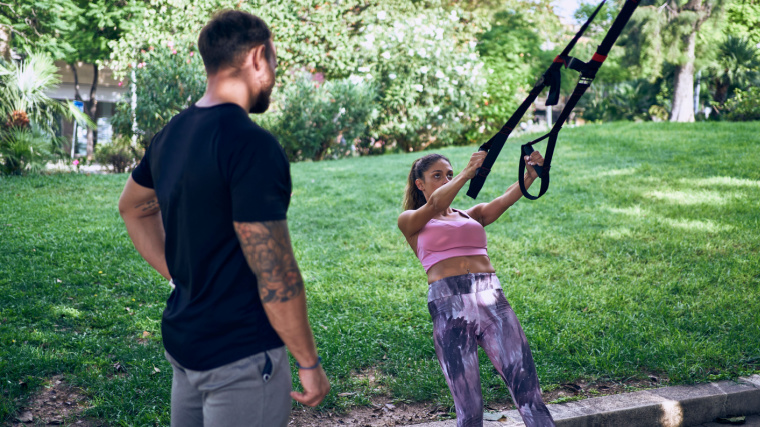 Personal trainer working with client outdoors performing cable row