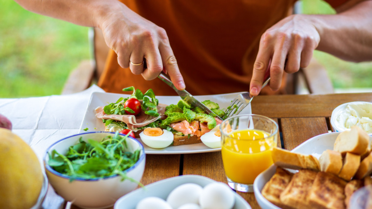 Muscular person outdoors eating big breakfast