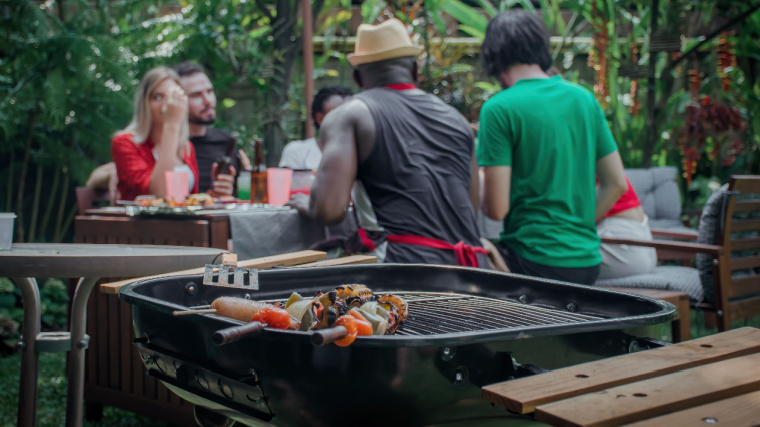 Group of people eating outdoors near grill