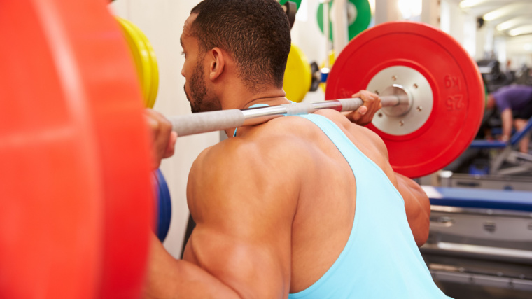 muscular person in gym doing barbell squat