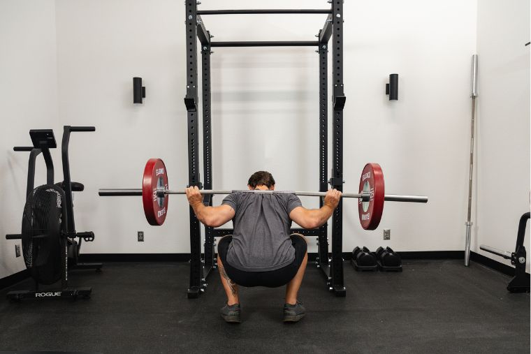 A young man doing squats outside the Titan X-3 Power Rack