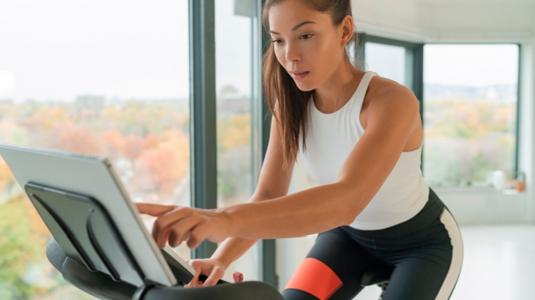 Long-haired person in gym using stationary bike