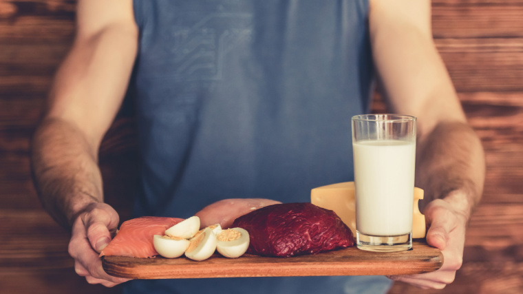 Muscular person holding tray of food