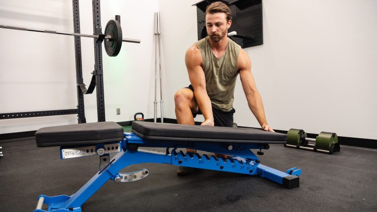 Pulse Beat Fit team member adjusts the REP Fitness BlackWing bench to a flat position.