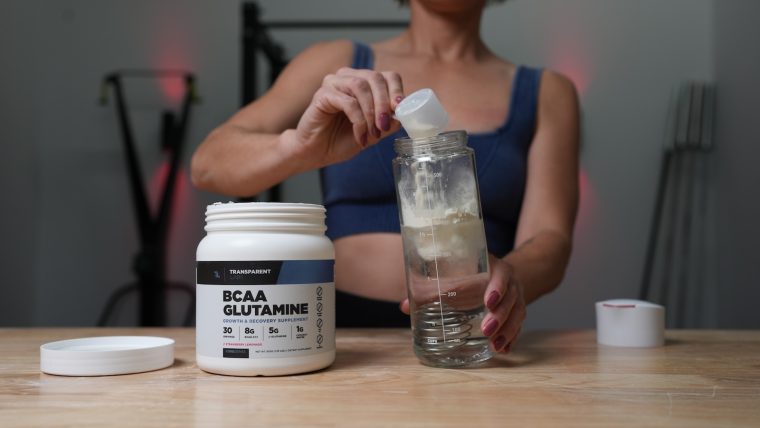 Pulse Beat Fit team member pours a scoop of Transparent Labs BCAA Glutamine into a bottle.